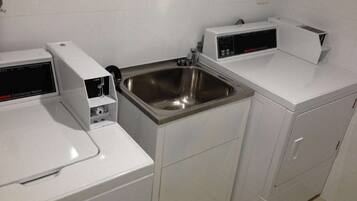A compact kitchen with a stainless steel sink, a commercial washer, and a microwave.