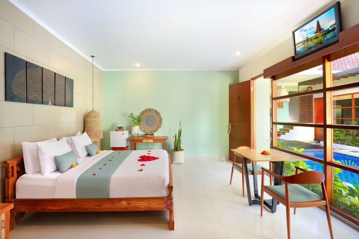 A bedroom with a bed, bedside table, and a TV mounted on the wall.