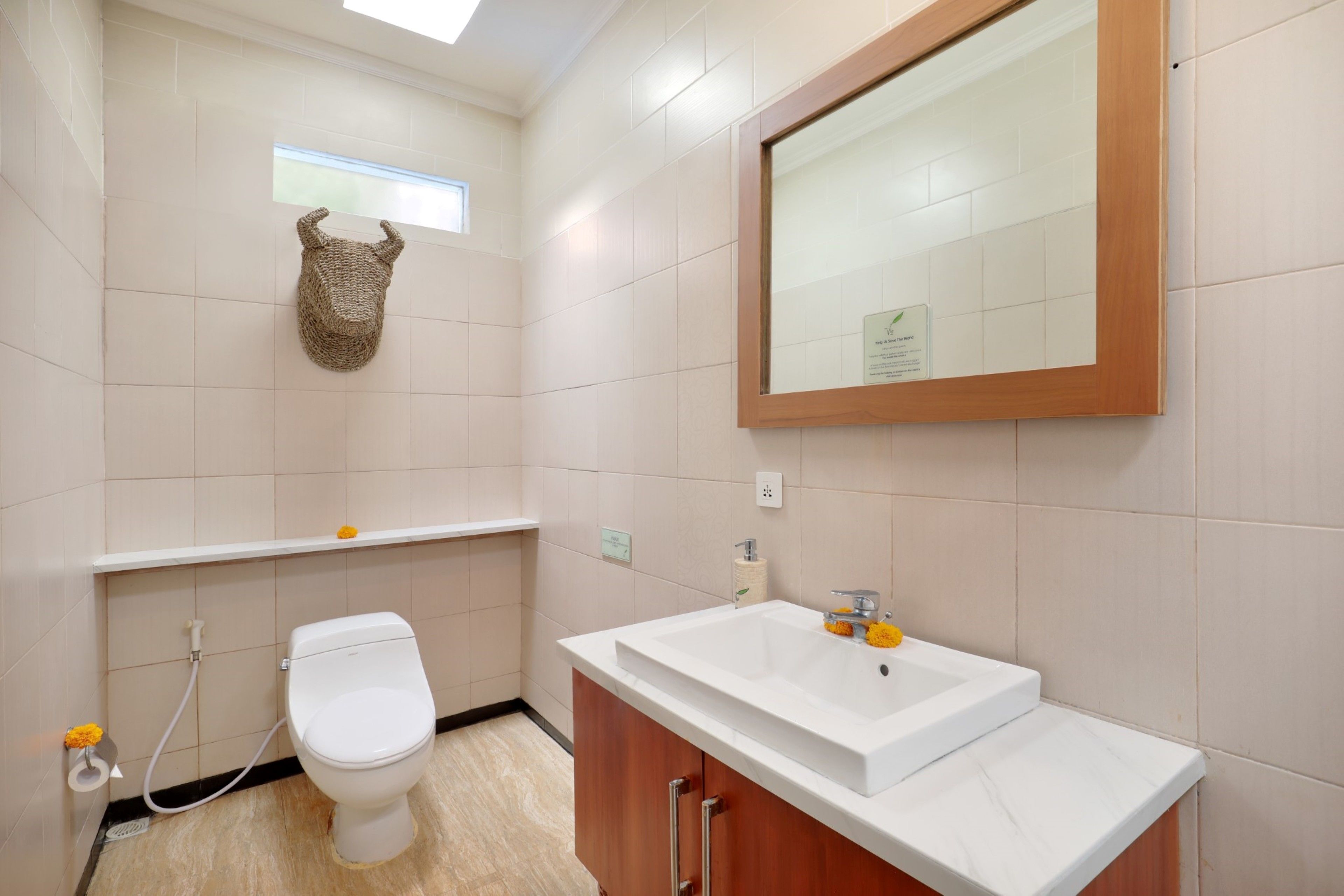 Een badkamer met toilet, wastafel, spiegel en een decoratief wandobject.