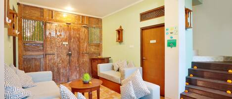 Un salón con un conjunto de sofás, una puerta de madera y una escalera decorada con flores.