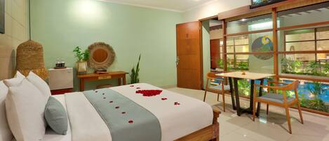 A hotel room with a bed, a desk, a chair, a TV, and a window with a view of a pool.