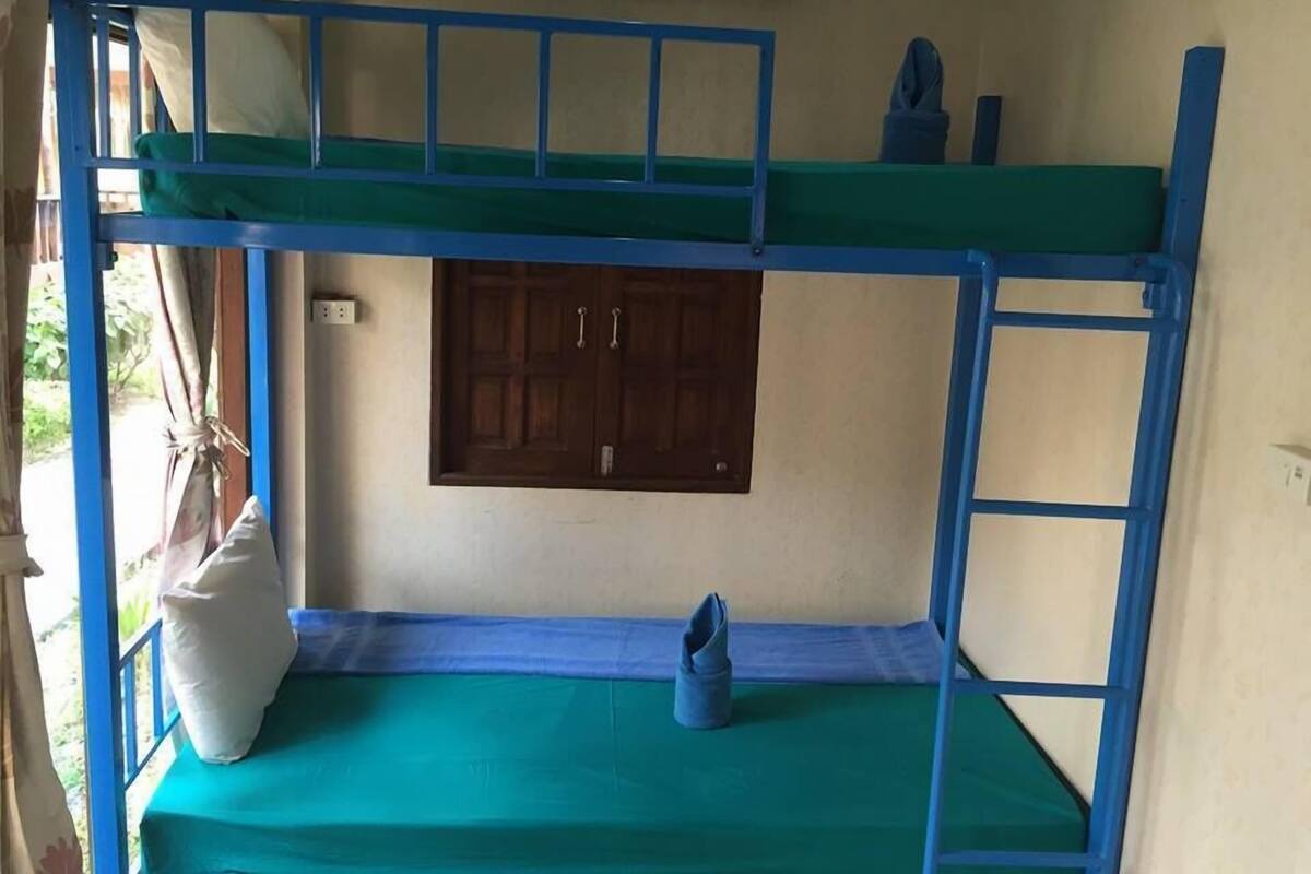 A bunk bed with a blue frame, a green mattress, and a wooden door in the background.