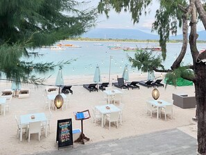 Ein Restaurant direkt am Strand mit Terrassenplätzen, einer Speisekarte und Booten im Hintergrund.