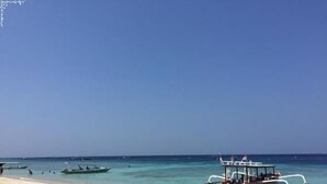 A beach with clear turquoise water, a sandy shore, and several boats.