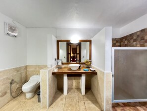 A bathroom with a toilet, a sink with a mirror, a shower area, and a tiled floor. - Laguna Gili Beach Resort (Gili Trawangan)