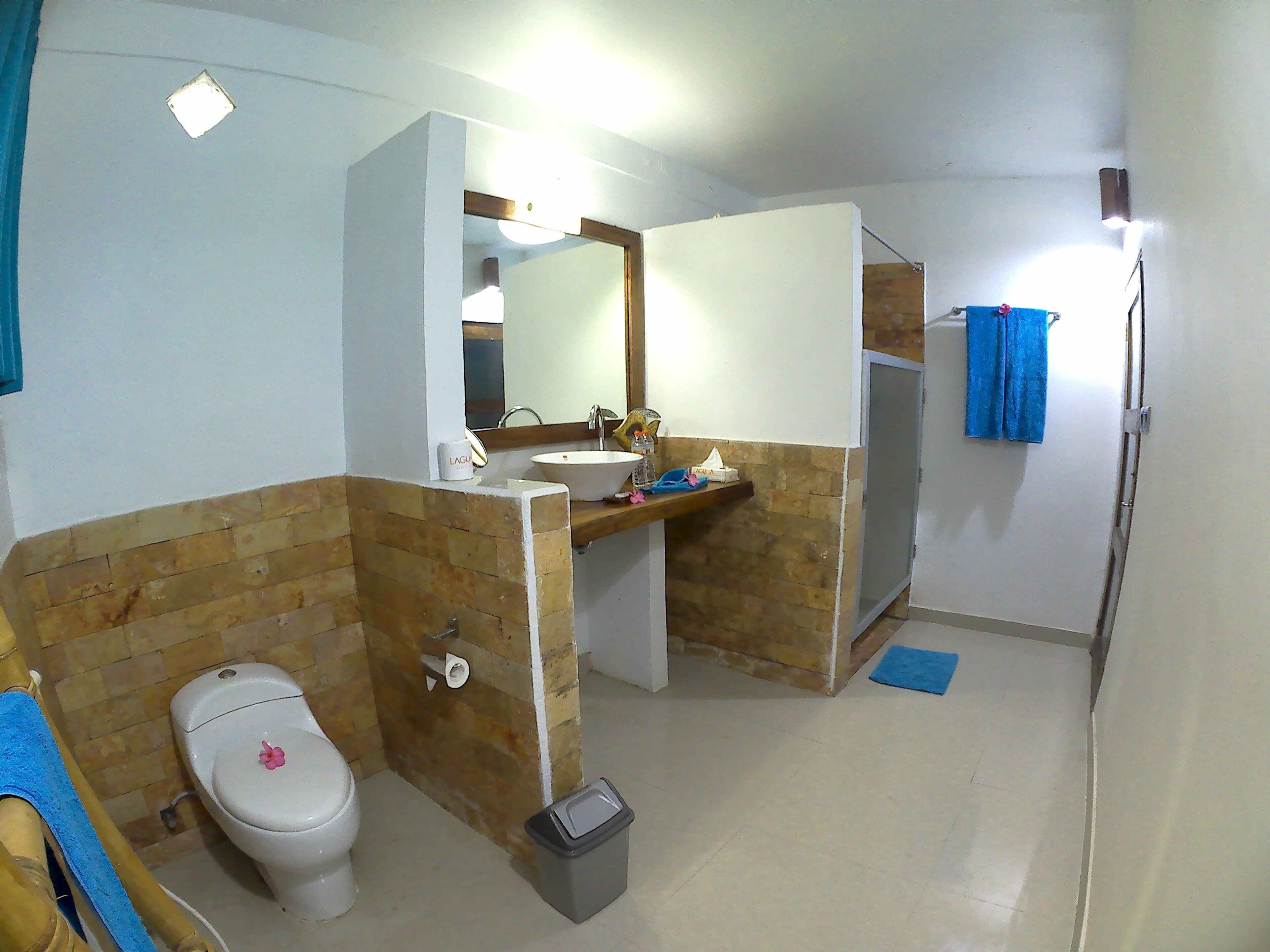 A bathroom with a toilet, sink, mirror, and shower area.