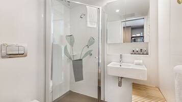 A modern bathroom with a glass shower enclosure, a white sink, and a mirror above it.