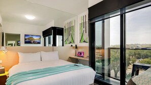 A modern hotel room with a large bed, a desk, a laptop, and a view of the city through large windows. - Mercure Bendigo Schaller (Bendigo)