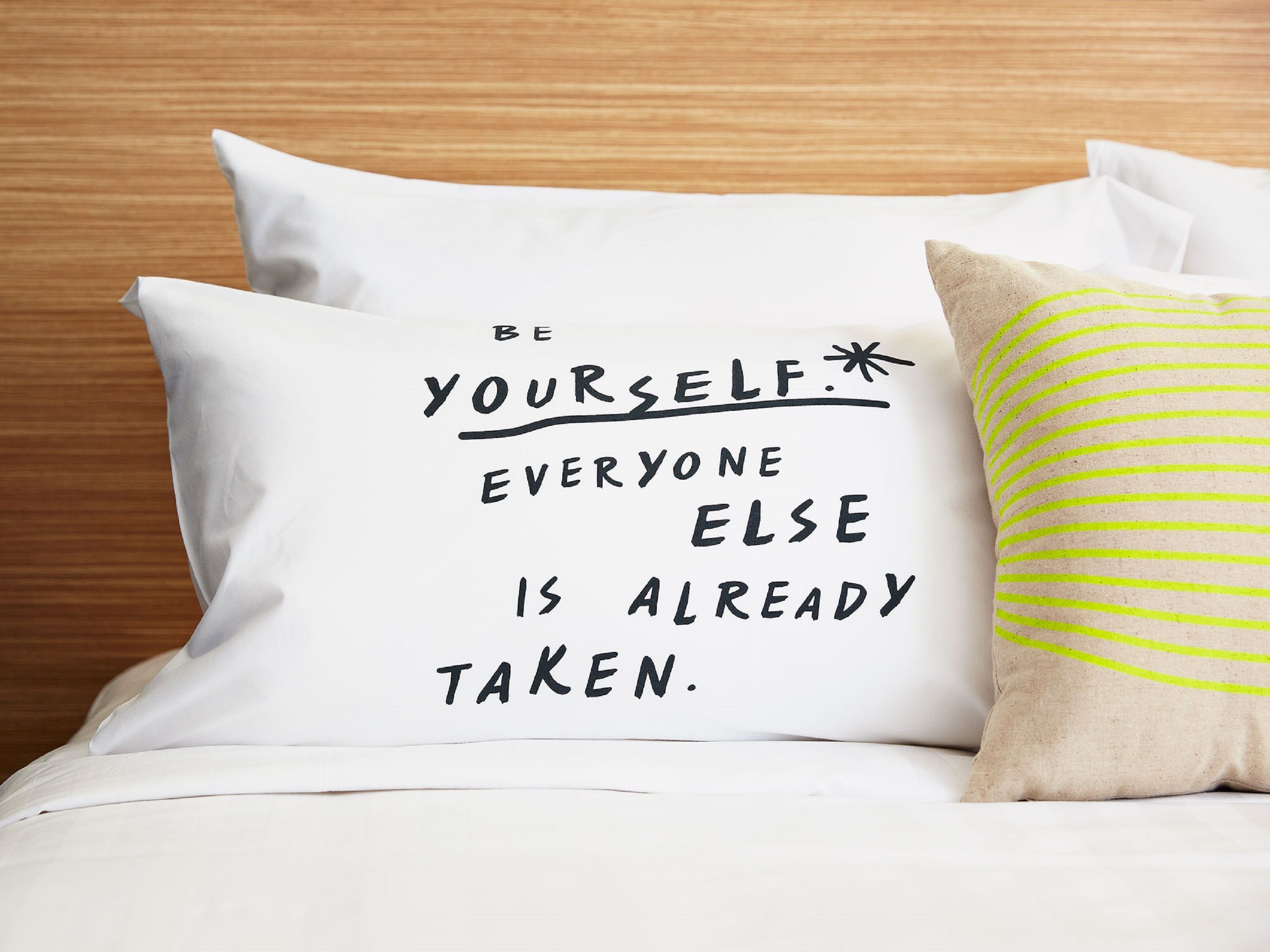 Una cama con un almohada que lleva una frase motivacional.