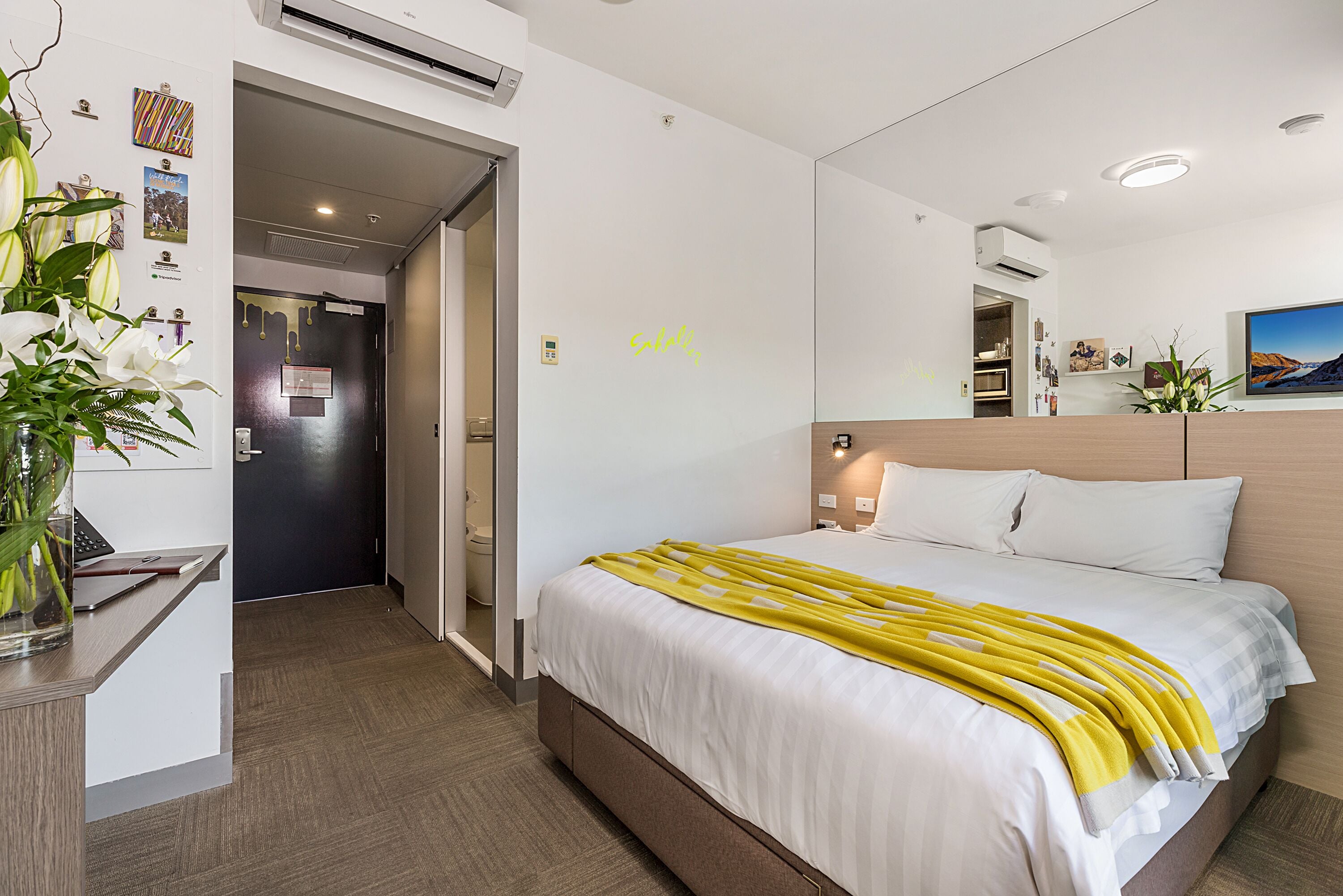 A hotel room with a bed, a desk, and a mirror.