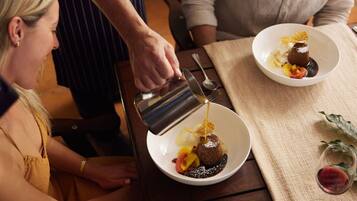 A person pouring a liquid into a dessert on a plate.