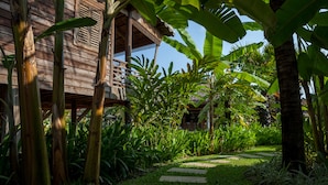 A wooden structure with a balcony, surrounded by lush greenery and a stone pathway. - Sala Lodges (Siem Reap)