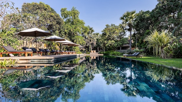 A serene pool area with lounge chairs and umbrellas, surrounded by lush greenery. - Sala Lodges (Siem Reap)