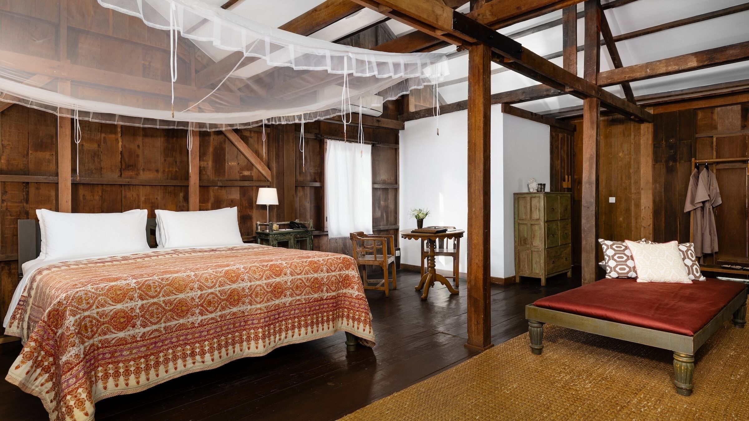 Una habitación rústica con una cama, una mesita y una silla.