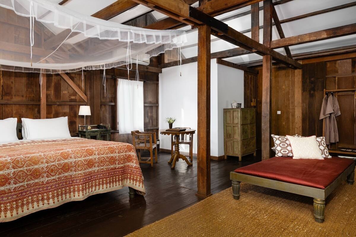 A rustic room with a bed, a small table, and a chair.