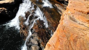A natural landscape with a waterfall, rocky terrain, and clear blue sky.