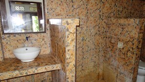 A bathroom with a mosaic tile wall, a white sink, and a mirror. - Banana Leaf Bungalows (Gili Trawangan)