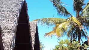 A thatched-roof structure with a narrow pathway leading to it, surrounded by lush greenery and palm trees. - Banana Leaf Bungalows (Gili Trawangan)