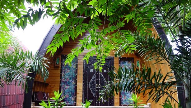 A wooden cabin with a balcony, surrounded by lush greenery. - Banana Leaf Bungalows (Gili Trawangan)