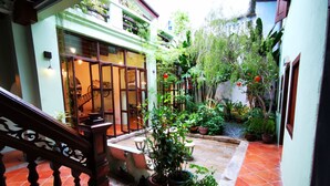 A courtyard with potted plants, a staircase, and a building with large windows. - East Indies Mansion (George Town)