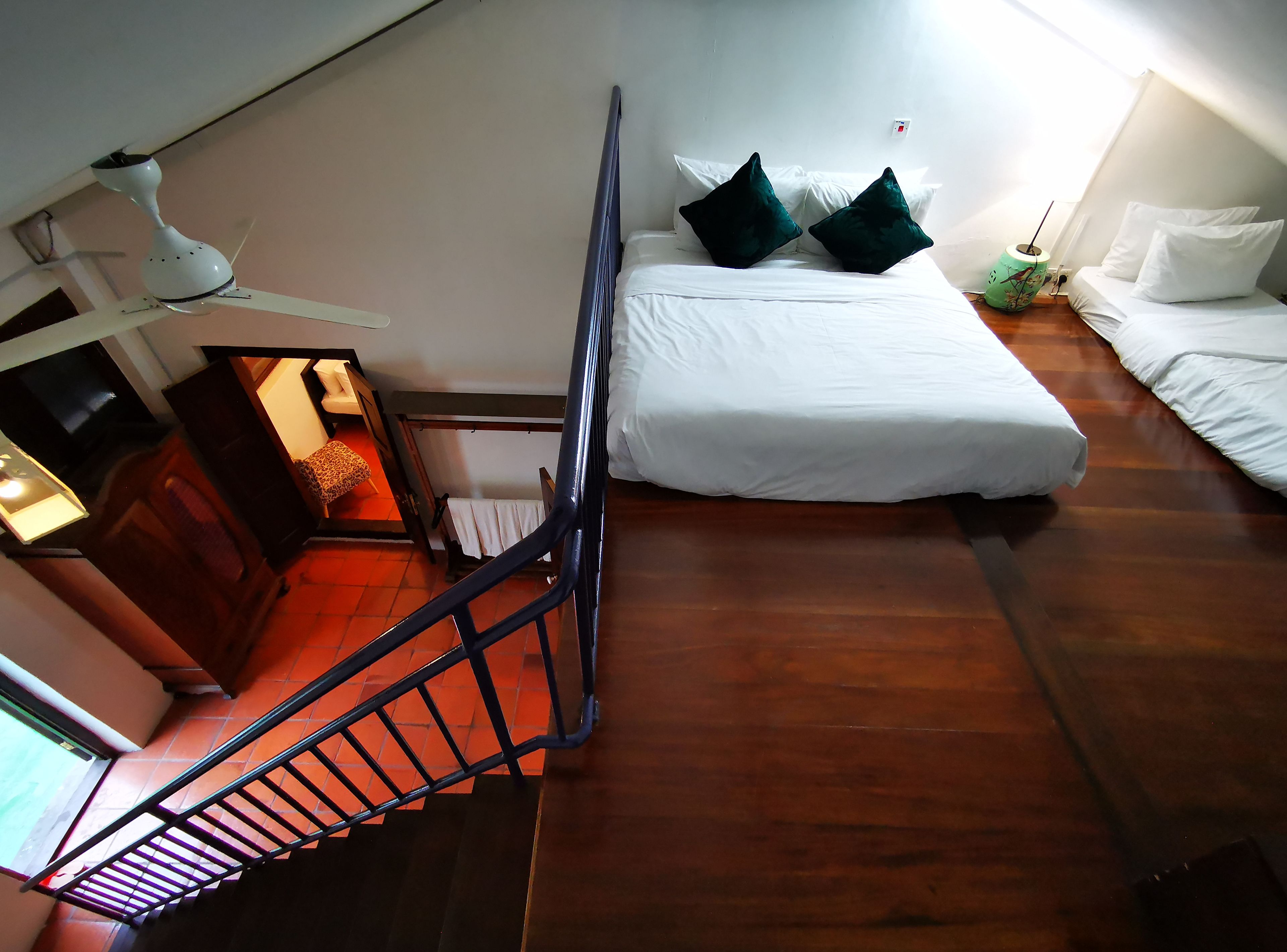 Een slaapkamer met een bed, twee kussens, een nachtkastje, een lamp en een raam.