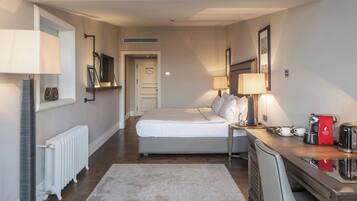 A hotel room with a bed, bedside lamps, a coffee maker, and a radiator.