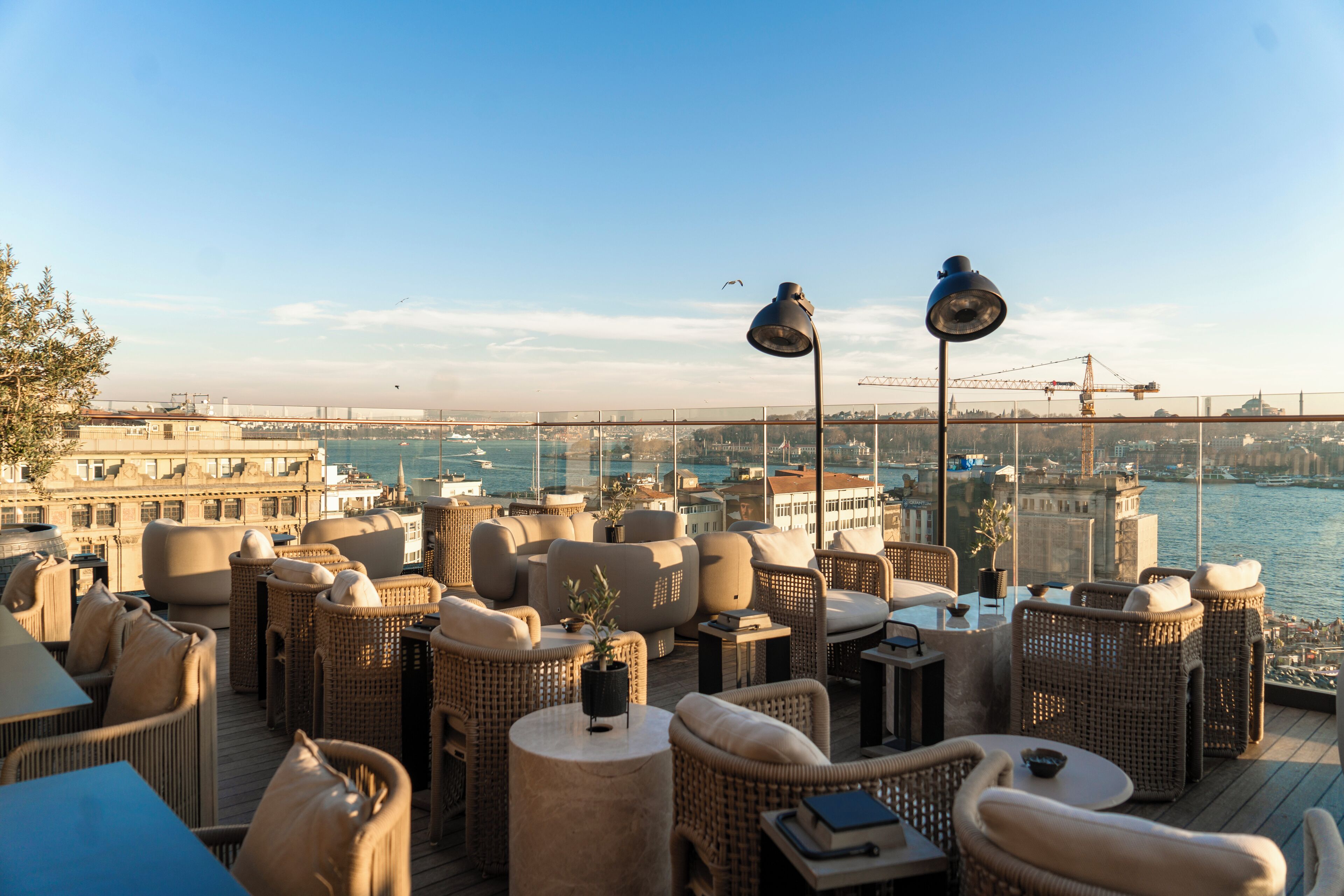A rooftop terrace with wicker furniture and a view of the city and water.