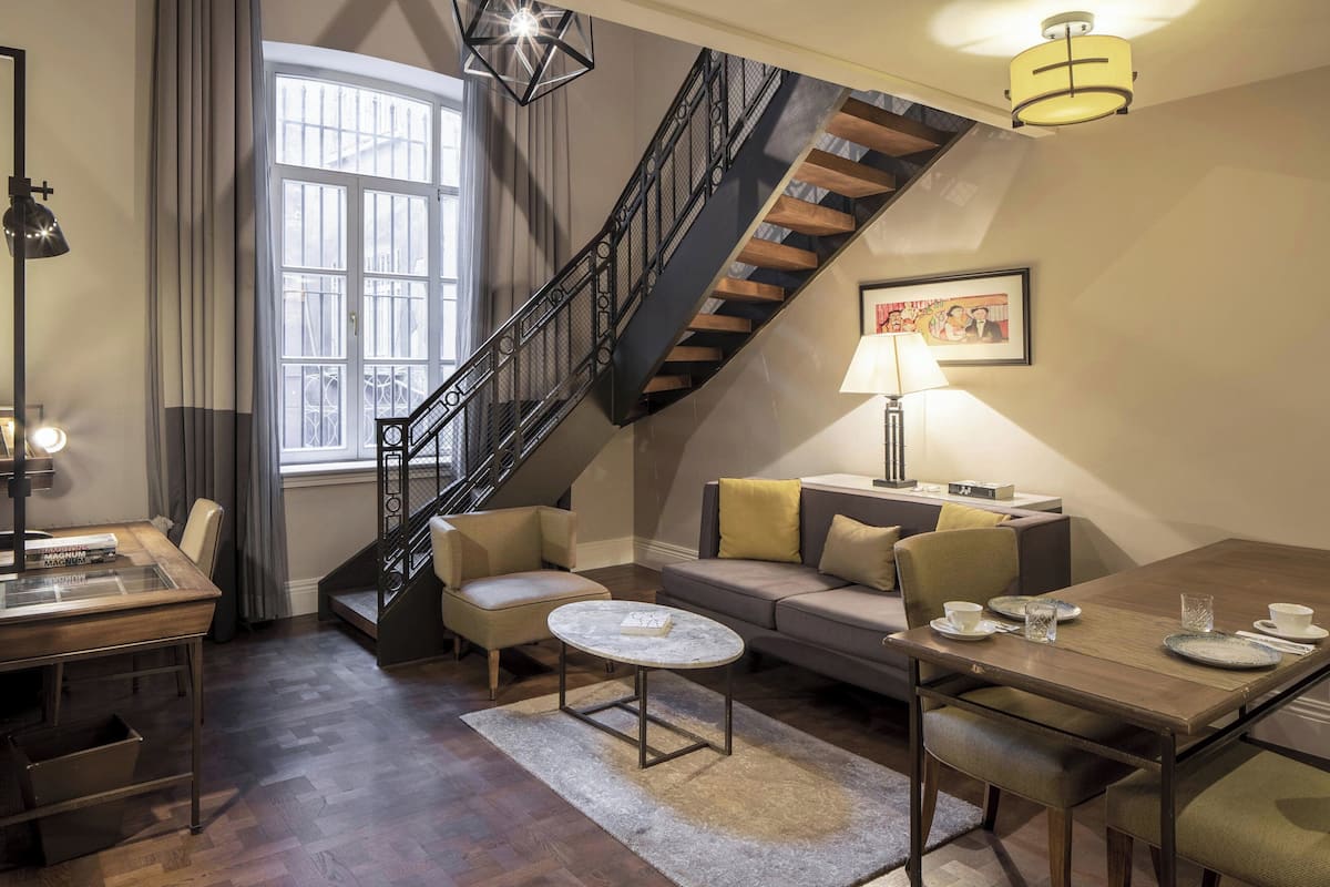 A modern living room with a staircase, a dining area, and a sofa set.