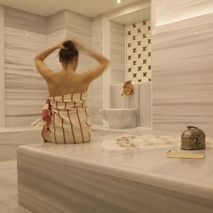 A bathroom with a marble countertop, a towel, and a decorative pitcher.