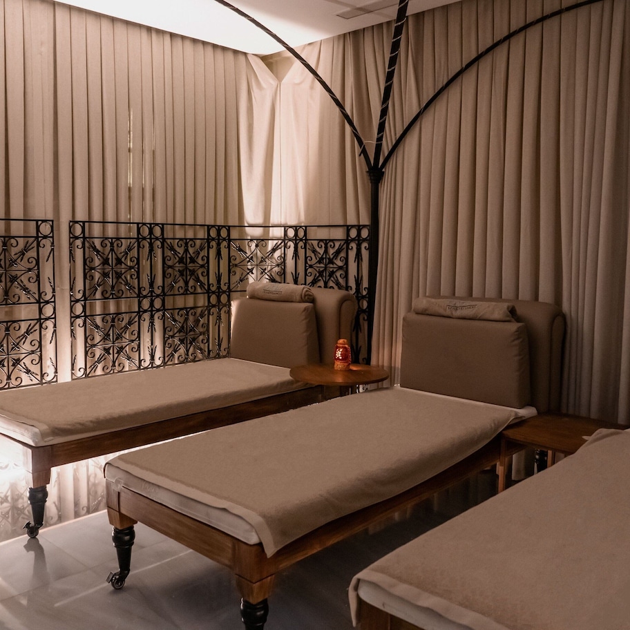 A room with two beds, a small table, and a decorative metal railing.