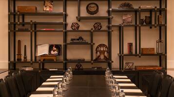 A conference room with a long table set for meetings, surrounded by chairs.