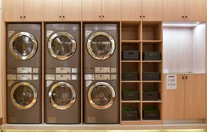 A laundry facility with six washing machines, each with a control panel and a digital display.