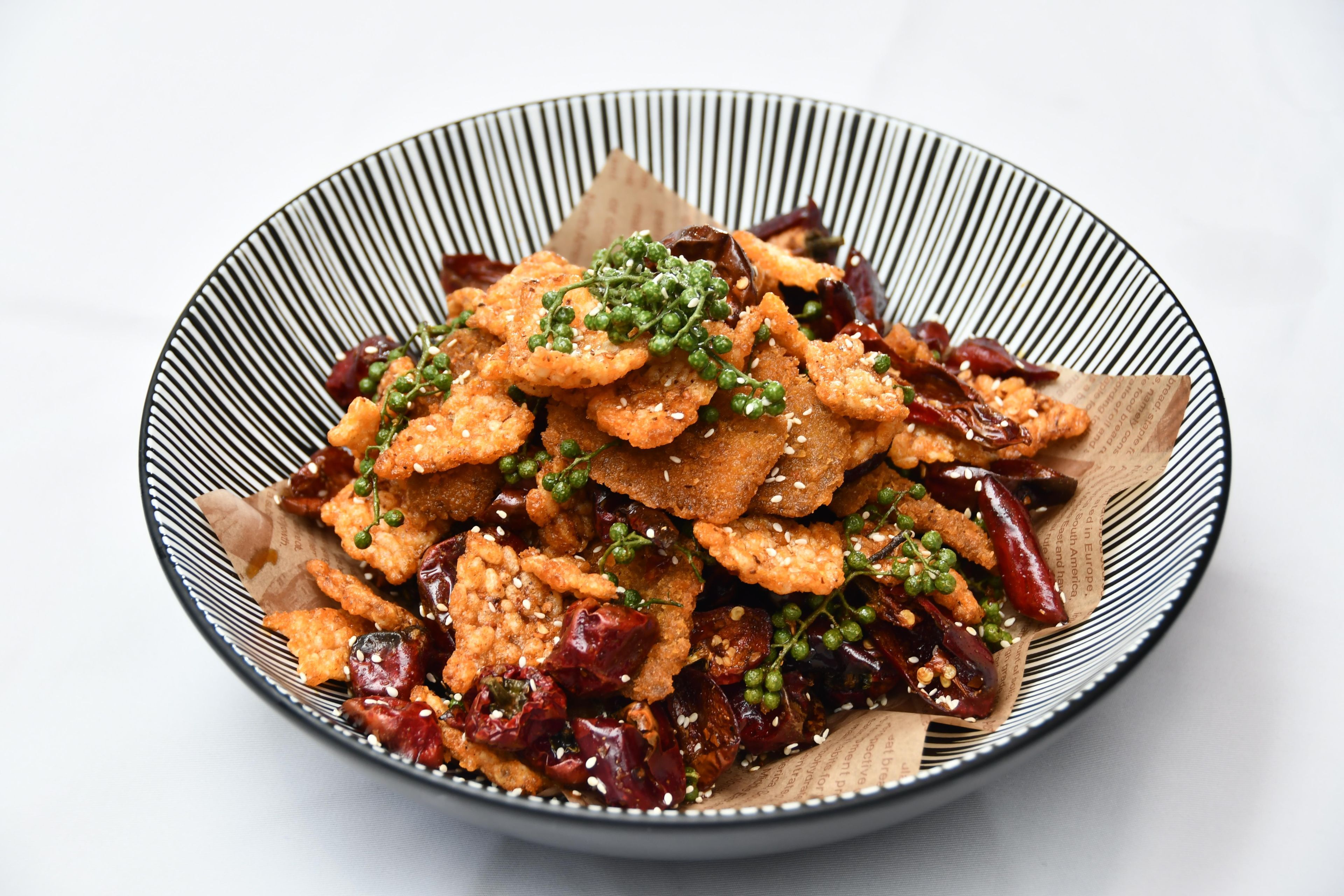 A bowl of food with sesame seeds and green garnish.