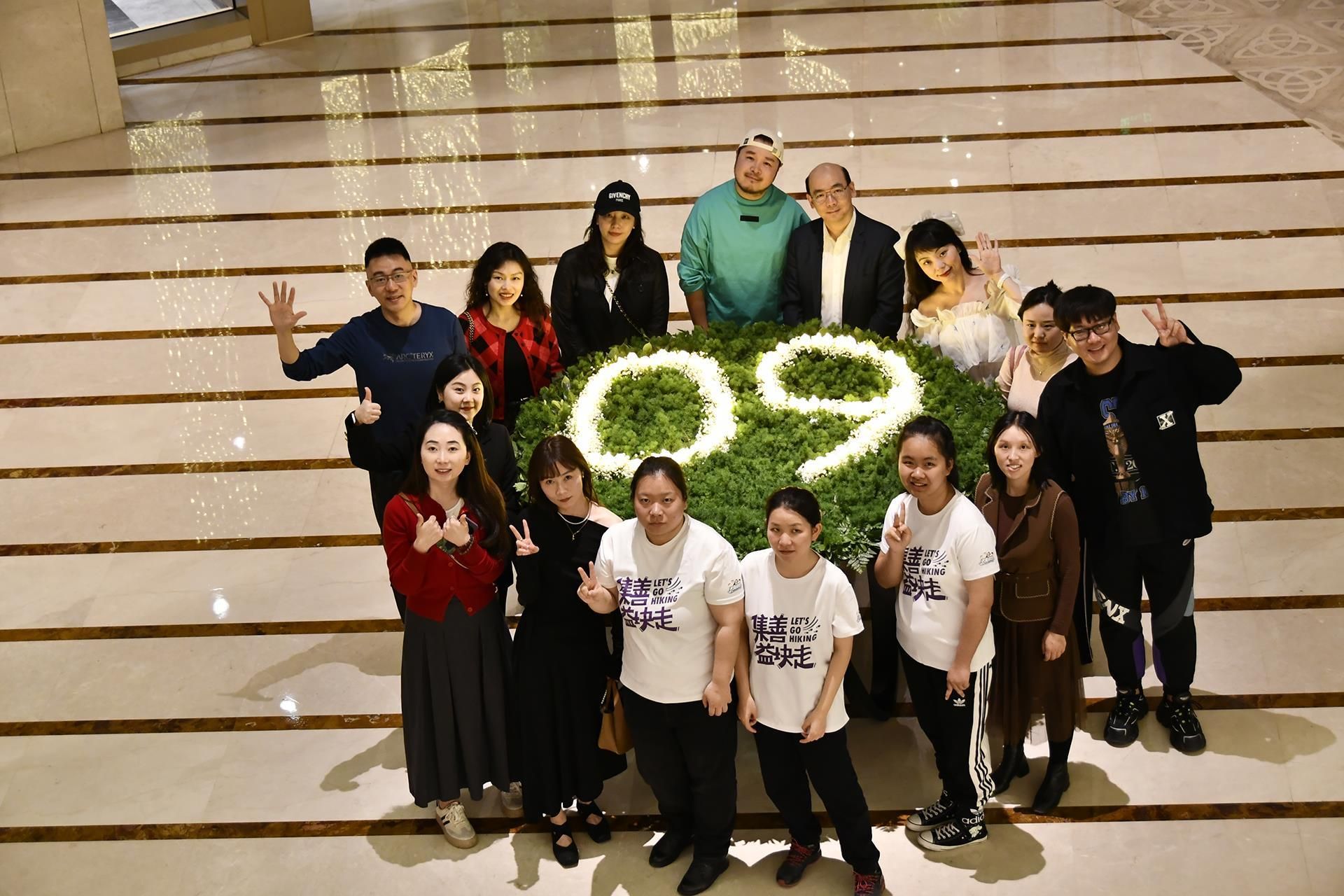 A group of people posing in front of a staircase with a decorative number '09' made of flowers.