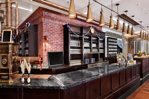 Un espace bar avec un mur en briques, des étagères remplies de verres et un comptoir en marbre.