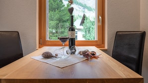 A wooden table with a bottle of wine, two wine glasses, and some decorative items. - Jolimont Apartments (Zermatt)
