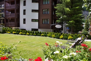 A well-maintained lawn with a row of sun loungers and a variety of flowers in the foreground.