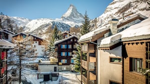 A snow-covered mountain village with wooden buildings and a prominent mountain peak in the background. - Jolimont Apartments (Zermatt)