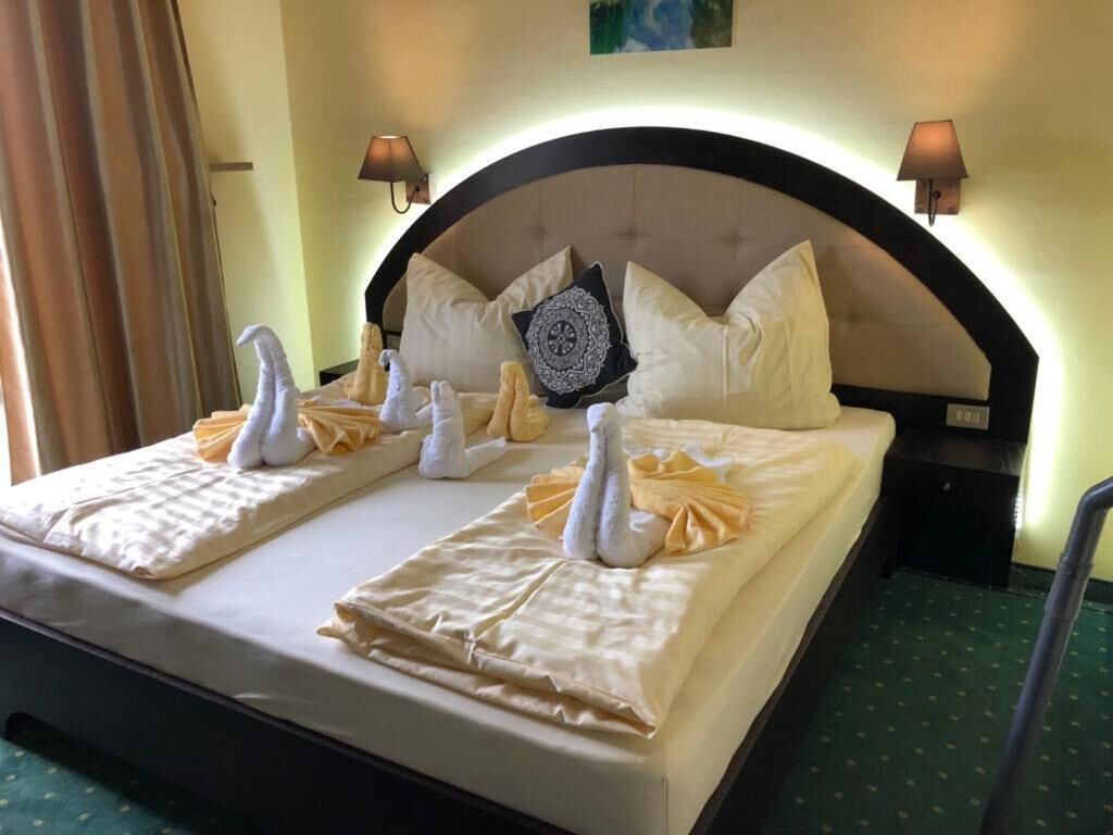 Ein Hotelzimmer mit einem ordentlich bezogenen Bett, zwei Wandlampen und einem dekorativen Kopfkissen.