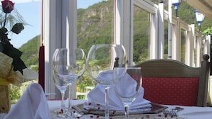 A table set for two with wine glasses, a plate, and a napkin, overlooking a mountainous landscape. - Hotel Unterinnerhof (Renon)