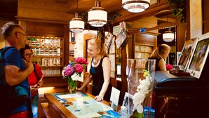 A reception area with wooden decor, a counter with various items, and hanging lights. - Hotel Unterinnerhof (Renon)