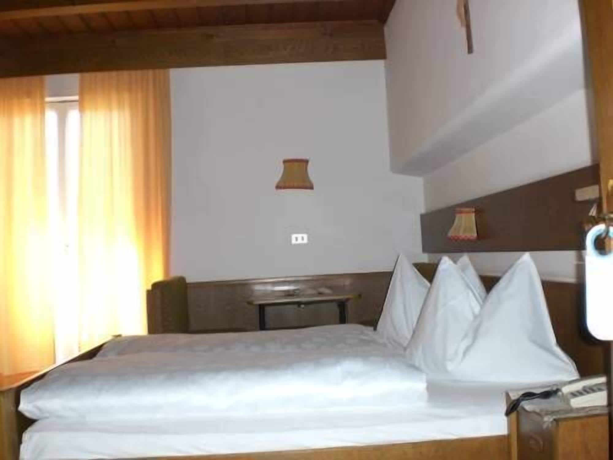 Una habitación de hotel con una cama, una mesita y una lámpara.