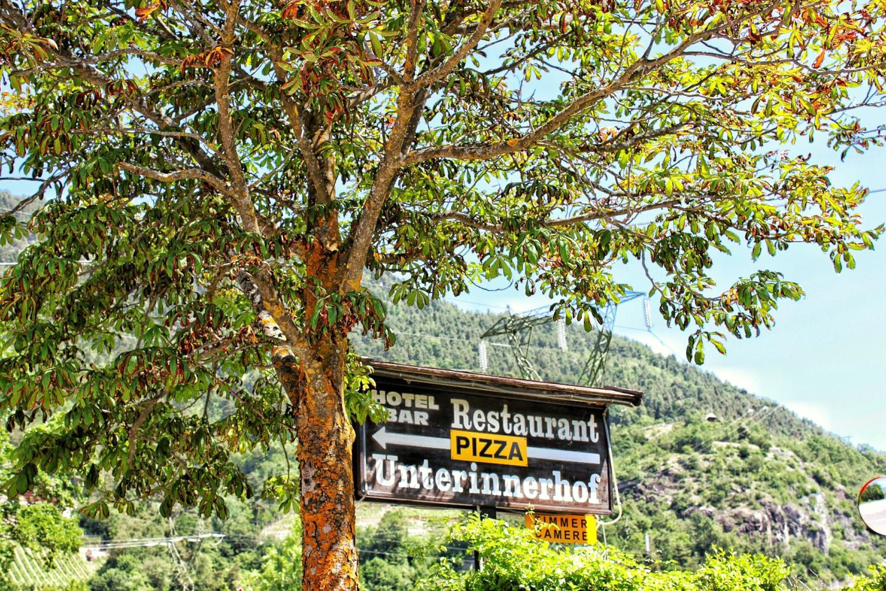 A signboard with directions to a restaurant, pizza, and an Unterinnerhof.