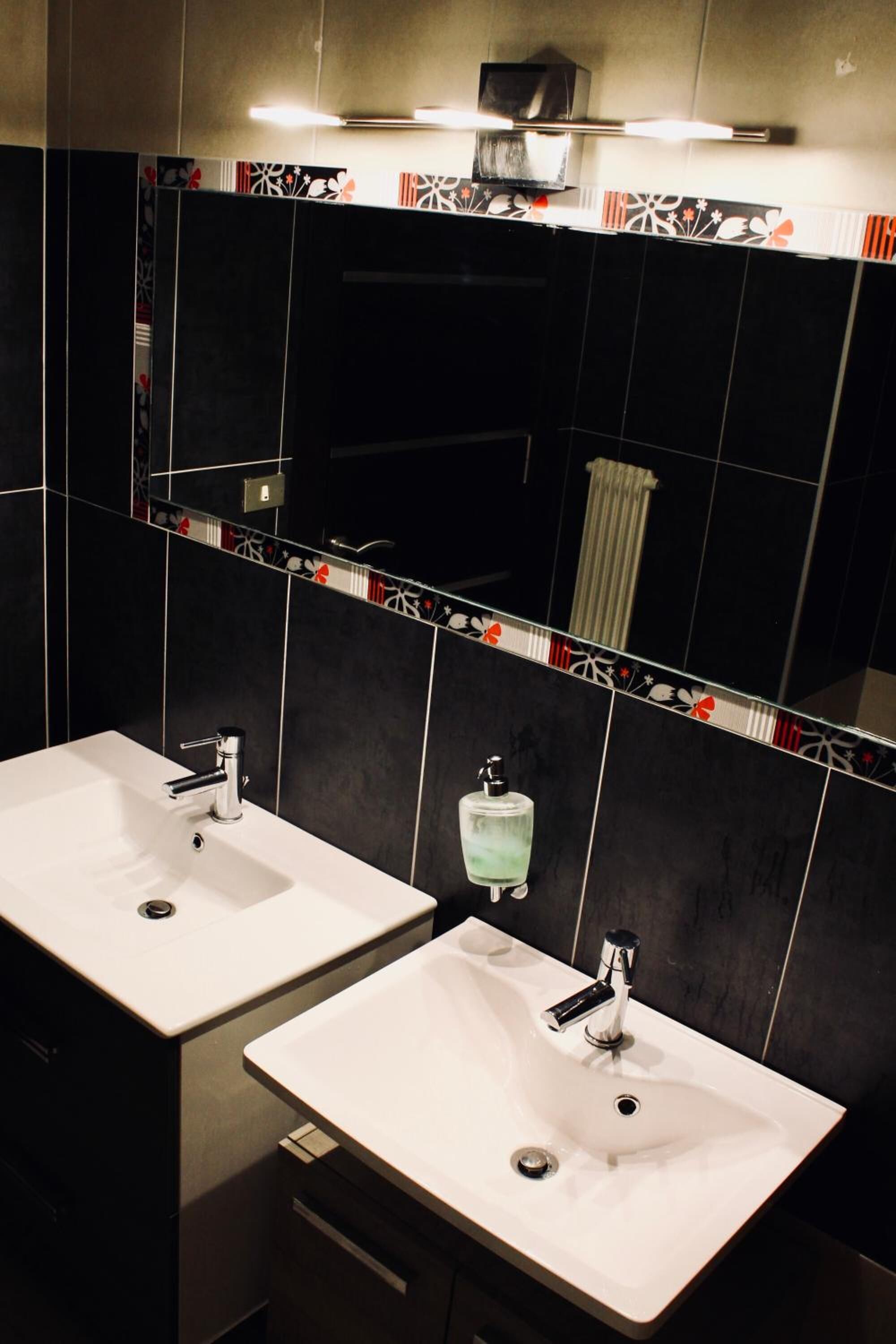 Un baño moderno con dos lavamanos, un espejo y un perchero para toallas.