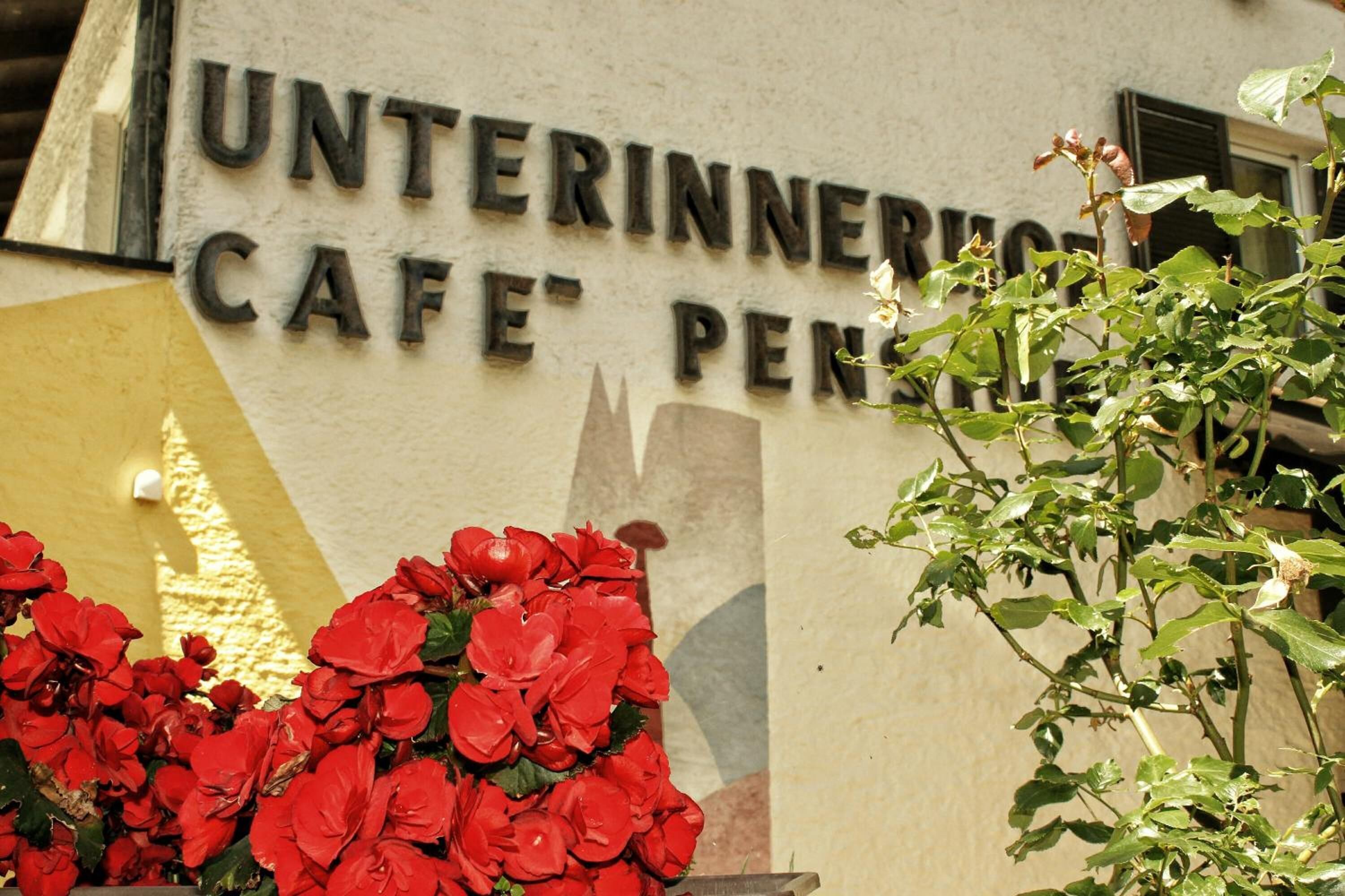 Een bordje voor 'Unterinnerio Cafe' met een decoratieve bloemstelling ervoor.