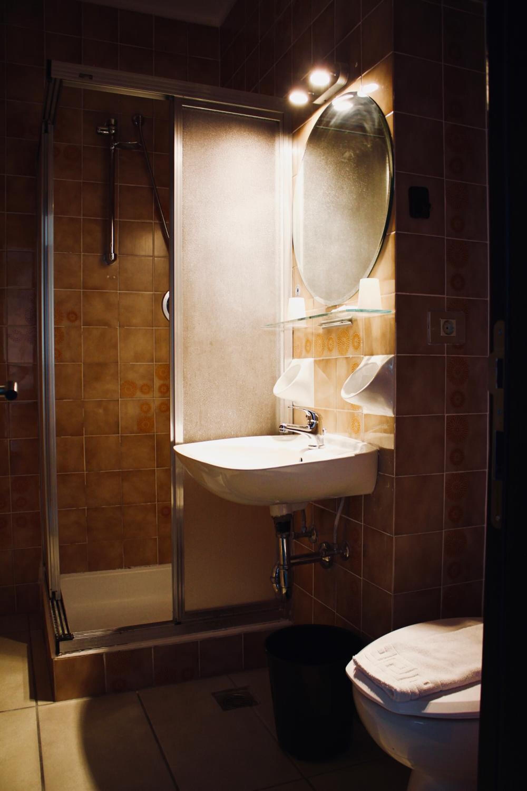 A bathroom with a glass-enclosed shower, a sink with a mirror above it, and a toilet.