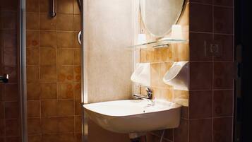 A bathroom with a glass-enclosed shower, a sink with a mirror above it, and a toilet.