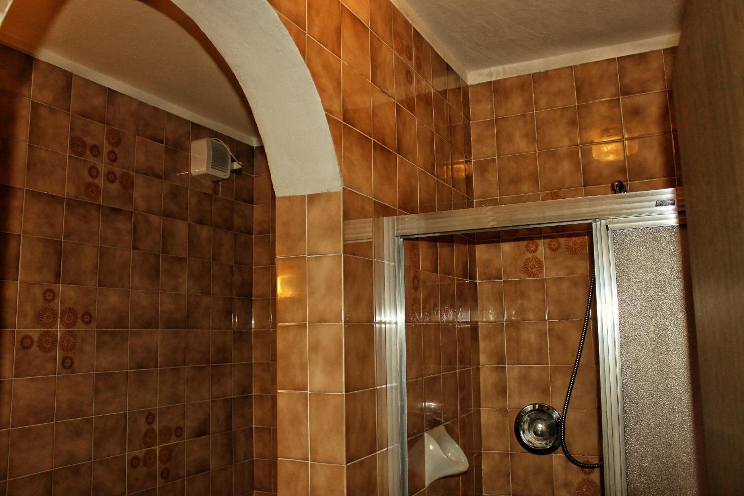 Un espace douche avec des carreaux marron et une porte en verre.