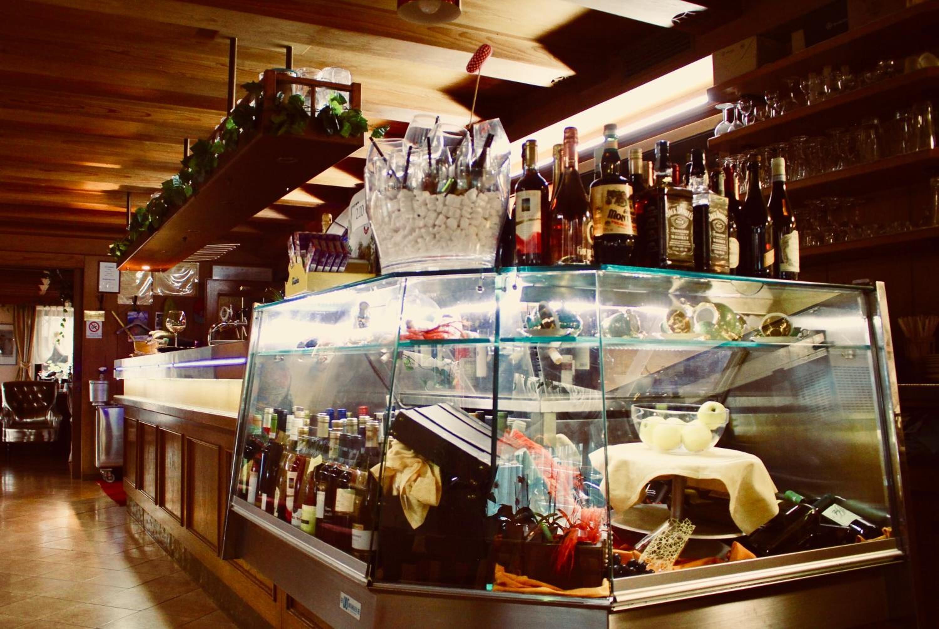 Un'area bar con una vetrina che espone bottiglie e un piccolo tavolo ricoperto da una tovaglia bianca.