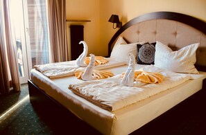 A hotel room with a large bed, a headboard, and a window with curtains. - Hotel Unterinnerhof (Renon)